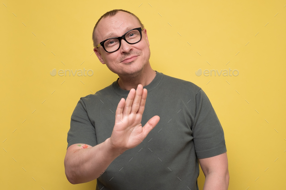 Attractive man in glasses shows refusal gesture, telling leave me in piece.