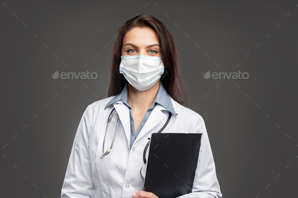 Female doctor in face mask with clipboard