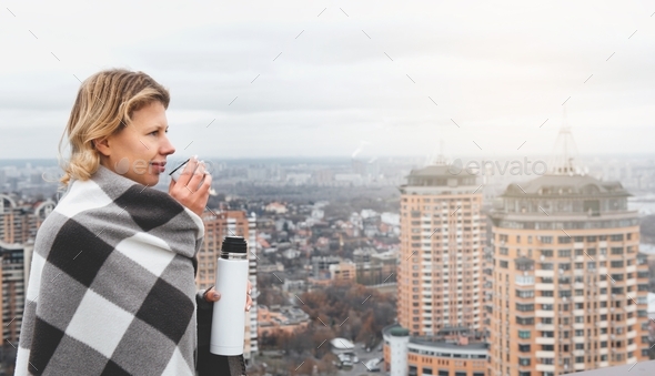 woman standing on the roof top while enjoying the beautiful view with drink
