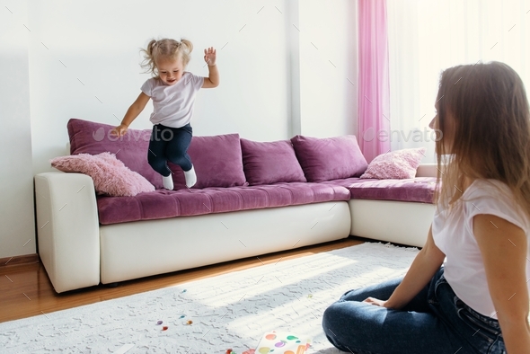 Little girl jumping from the couch, activity at home, parental control and security for kids, full o