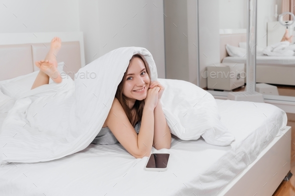 woman waking up in the morning in bed, covered in blanket Stock Photo ...