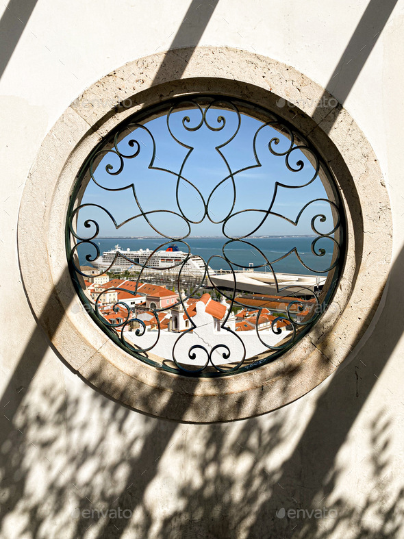 Shadow in the form of parallel diagonals on a wall with a round window overlooking the Lisbon port