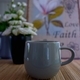 Close up of a coffee or tea mug on wooden table having blurred image of roses vase in background - PhotoDune Item for Sale
