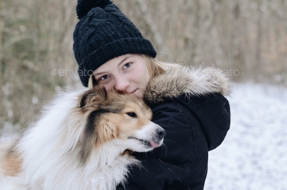 Photo of a young girl cuddling a dog outside in winter