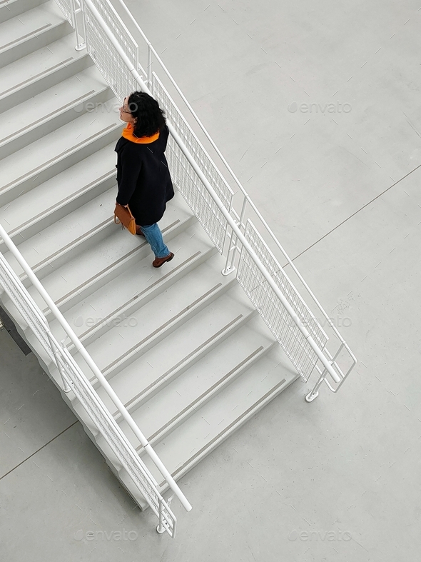 mature woman in fashionable clothes climbs the white stairs - Stock Photo - Images