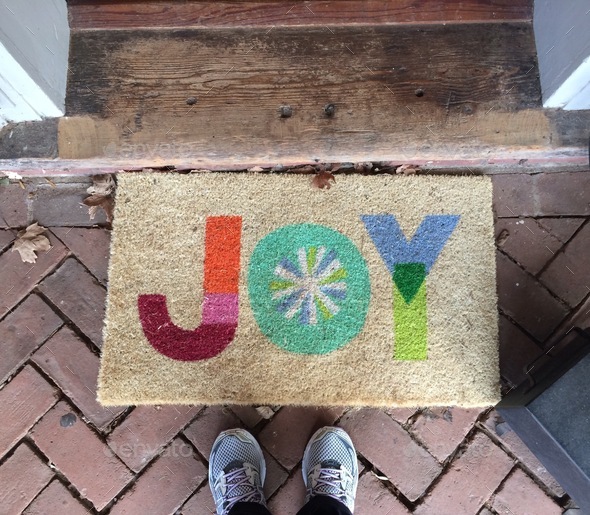 Christmas “Joy” entrance doormat at home. Looking down. Feet. Homes & neighborhoods. Real state
