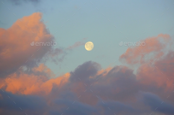 Beautiful sunrise sky reflected in the clouds with the moon setting.