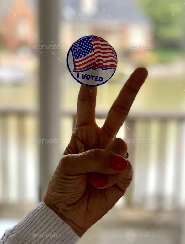 Woman with an I voted sticker in her fingers with the victory sign. A citizen duty & civil right.