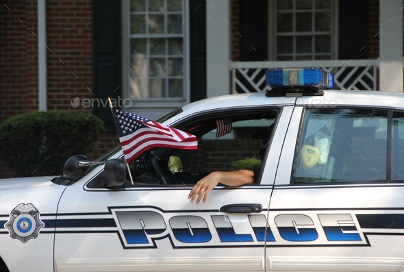 Police car with the United States flag during a July 4th parade offering safety to the community