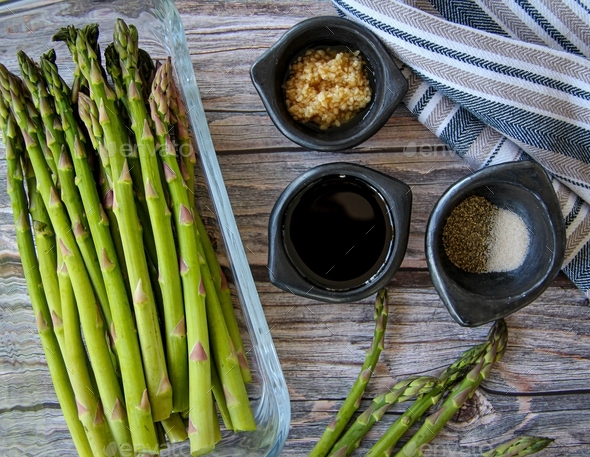 Cooking asparagus flat lay with ingredients as olive oil garlic & salt on a wooden textured surface