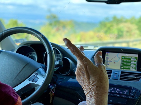 Hand of an elderly woman pointing to something that caught her attention during road trip