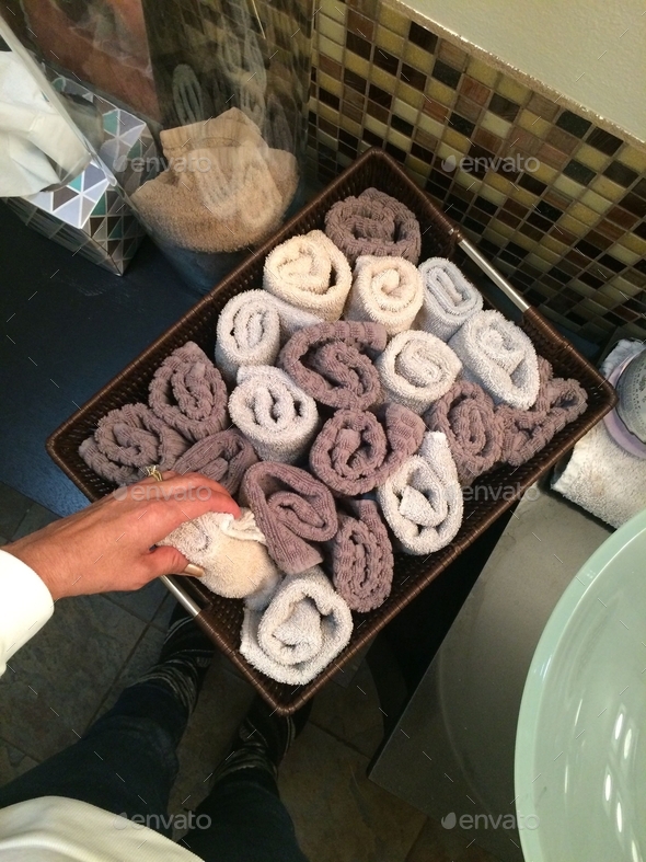 Overhead of woman in bathroom grabbing a towel from basket with
