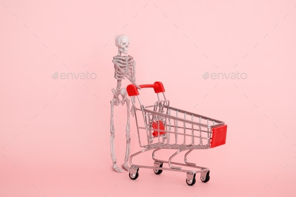 human skeleton with shopping trolley on a pink background selective focus