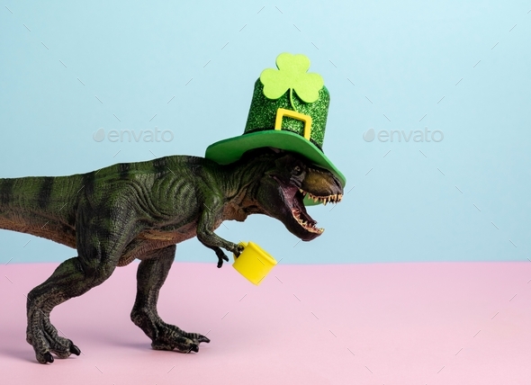 Cute st. Patrick card with dinosaur wearing green hat and holding green ale pastel pink and blue