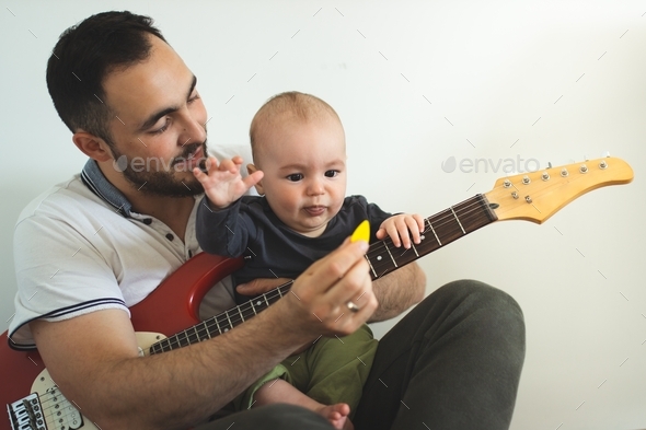 Dad and son playing guitar. A father teaches his son how to play the guitar properly.