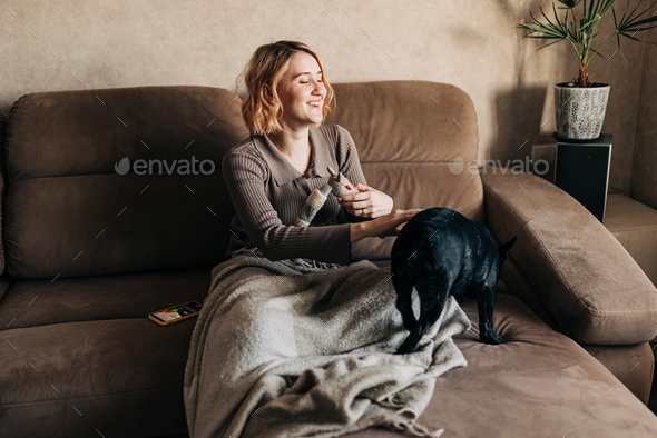 Young woman with her pet French bulldog on the couch lifestyle authentic people with pets