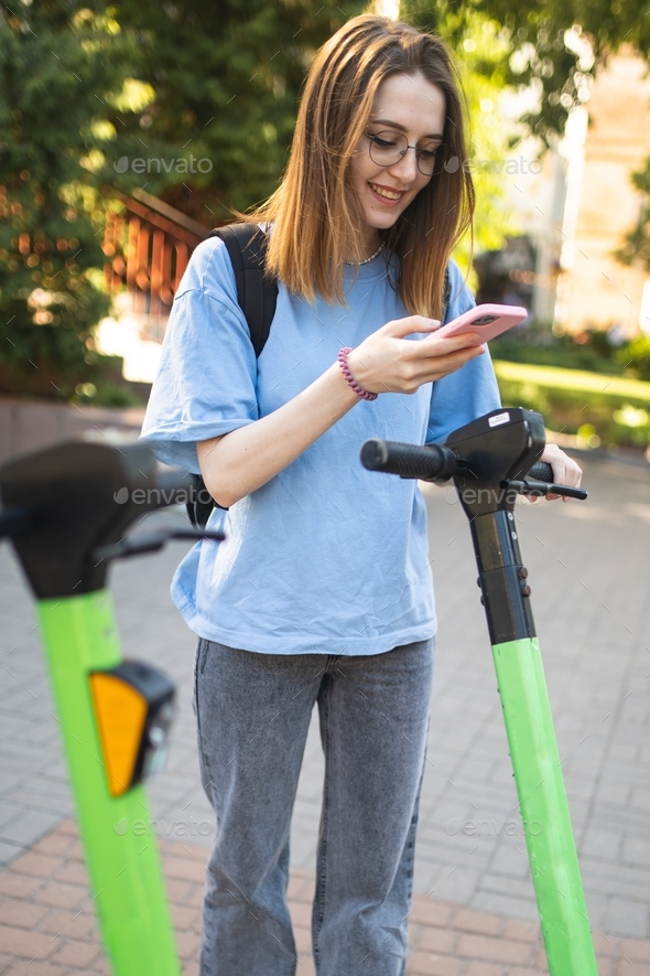 The girl rents a scooter. Scooter rental. Ecological mode of transport. A walk around the city.  - Stock Photo - Images
