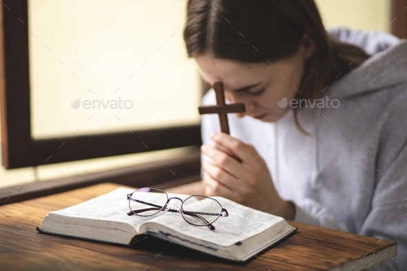 The girl reading the Bible and prays. Prayer. Faith and religion. Believing girl praying. Bible.