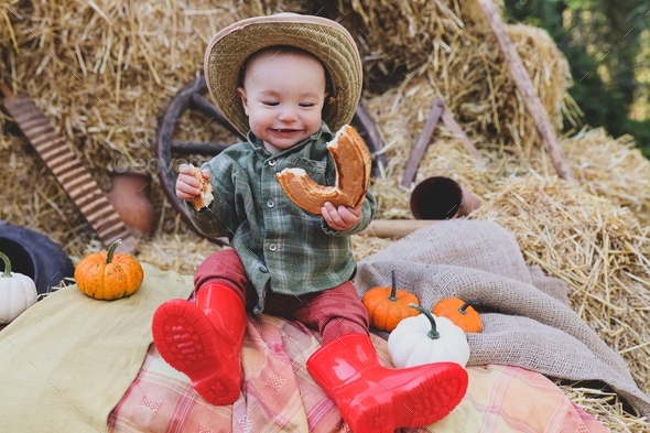 Little and funny boy with a booth in his hands. Farm life. Autumn atmosphere. Autumn time.