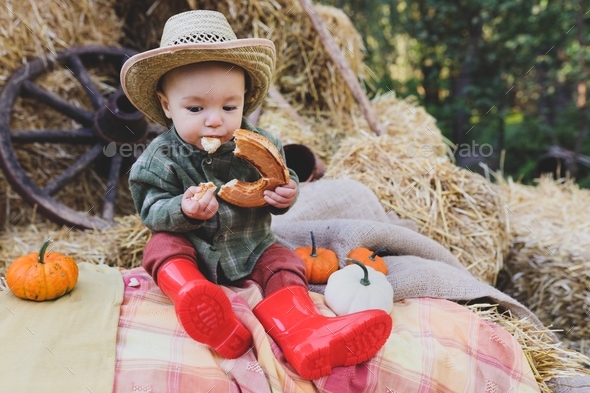 Little and funny boy with a booth in his hands. Farm life. Autumn atmosphere. Autumn time.