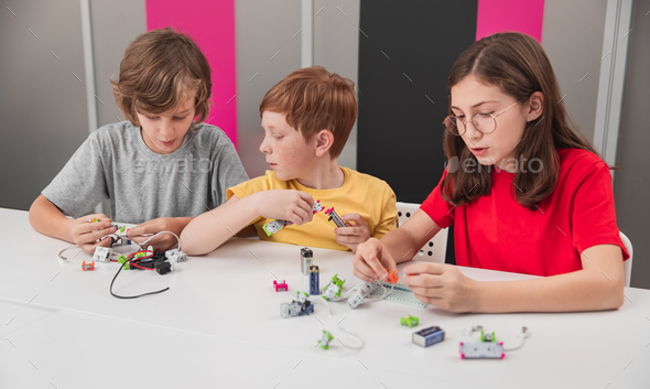 Children constructing electronic robots in classroom