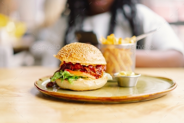 African woman with afro hair eating a tasty classic burger with fries. Cheat Meal.