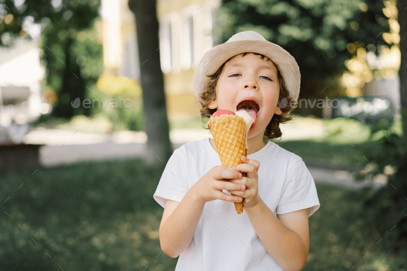 Boy in a hat is holding an ice cream and looks happy and surprised ...