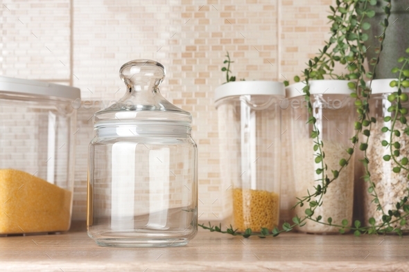 Glass cookie jar mock up. Transparent jar mockup against background of kitchen and plastic container