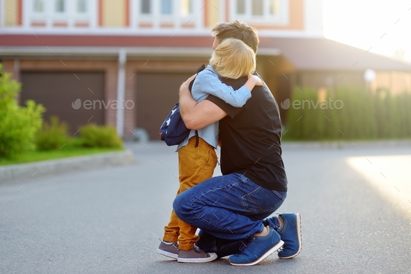 Little boy says goodbye and hugging to father before going to school. First day of school.