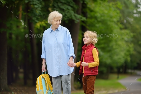 Beautiful gray-haired elderly lady accompanies or pick up baby from school.