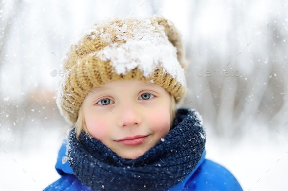 Unny Little Boy In Blue Winter Clothes Walks During A Snowfall 