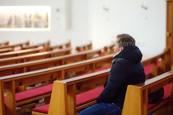 Religious middle age man praying in catholic church. Person closing his eyes, begging for forgivenes