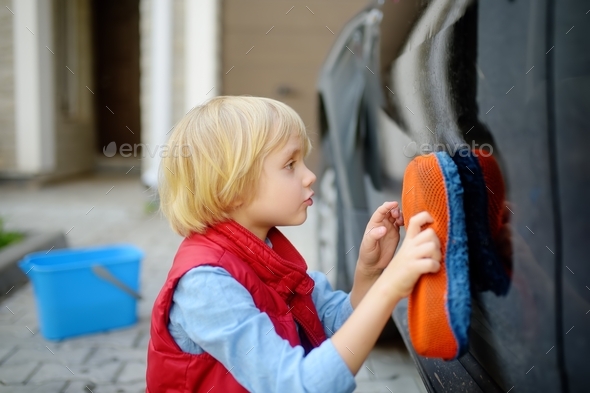 Preschooler boy helping his father washing family car. Little dad helper.