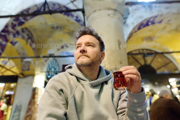 Mature man drink turkish tea sitting in small cafe in the Grand Bazaar in Istanbul, Turkey