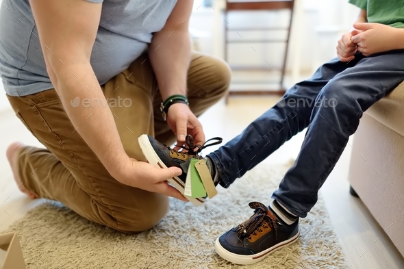 Online shopping for baby and kids. Father helping fitting shoes for his child at home.