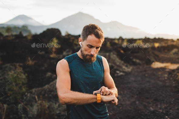 Runner checking training results on smart watch. Male athlete using fitness tracker.