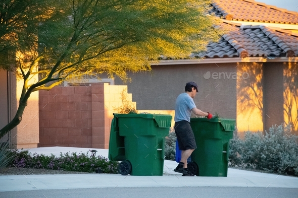Man putting out the garbage bins for trash collection.