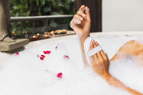 Woman Washing Hands In Bath Tub With Foam Bubbles And Use Jute Sponge