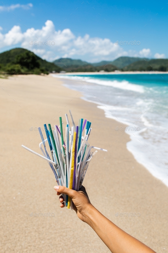 Hand holding heap of used plastic straws on background of clean