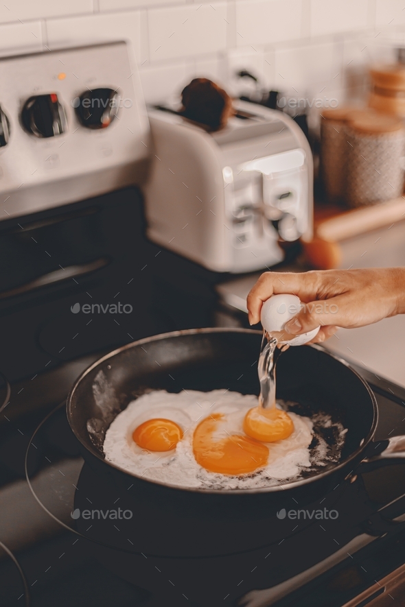 Making fried eggs for breakfast. Cracking egg into the pan. Egg yolks