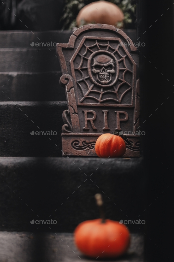 Halloween decorations on stairs of the house. Dark colors. Black, orange. Grave, pumpkins. Scary,rip