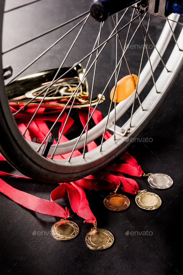wheelchair standing on gold medals with red ribbons and champion goblet on black floor