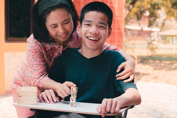 Disabled child on wheelchair is interested in skills development toy block wood with his parent - Stock Photo - Images