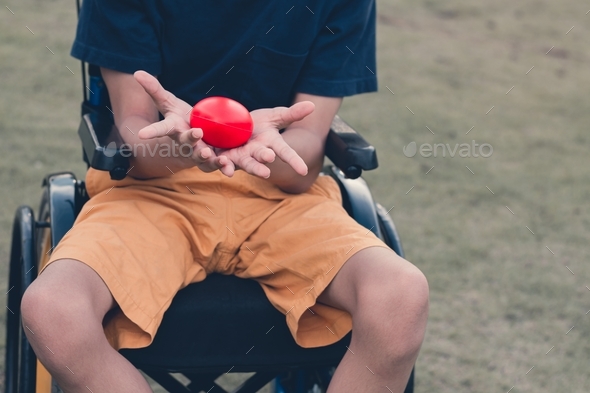 Disabled kid on wheelchair and the red heart in his hands, Encouraging from someone.