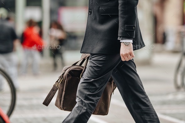 Businessman at evening formal outfit clothes walking on city street to office with brown bag