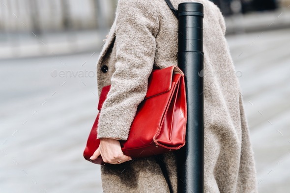 Blond business woman from behind walking on street near building with red bag and tubus