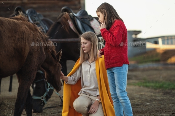 two sisters get to know the horse, the older sister strokes the horse on the head