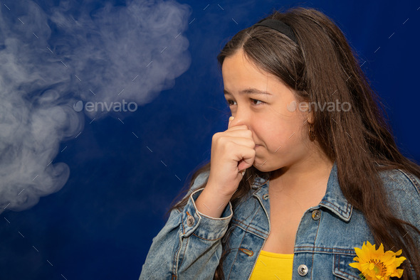 Passive smoking concept. Teen girl pinch her nose because toxic fumes from car.