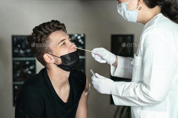 the doctor takes a swab from the young man\'s nose, DNA test, PCR test