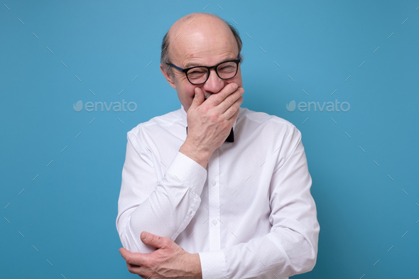Senior man laughing and embarrassed giggle covering mouth with hands